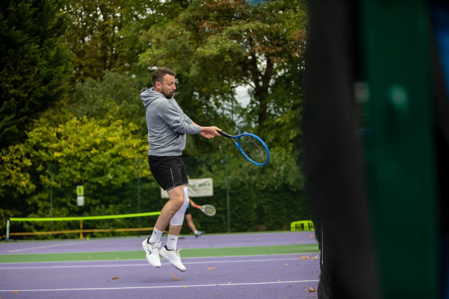 Adult tennis player jumping to play a shot on an outdoor court