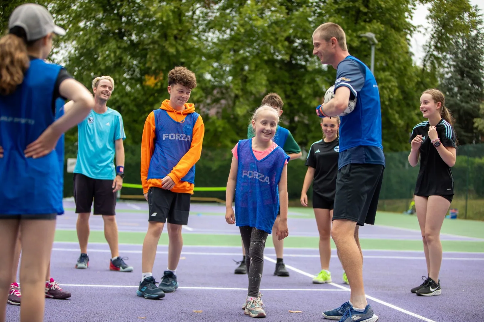 Tennis coach leading a group of young players through a court activity