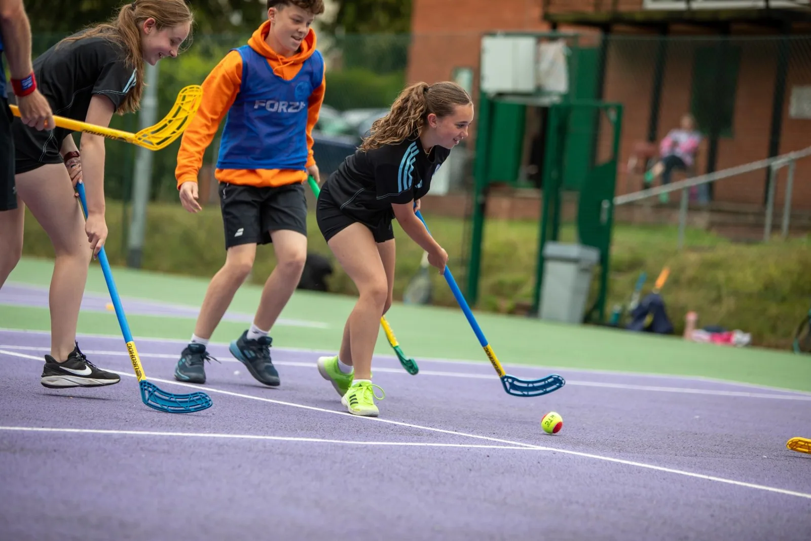 Young players taking part in a hockey activity with sticks on an outdoor court