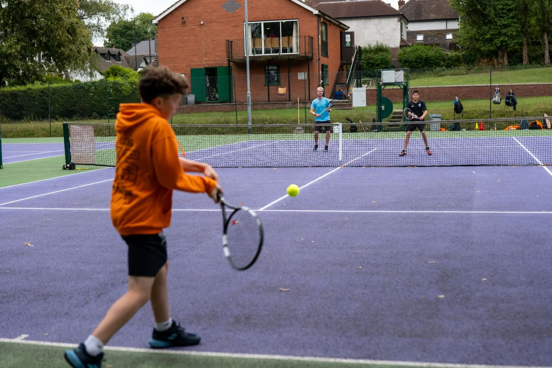 Young tennis leader playing a shot across the net during a group session