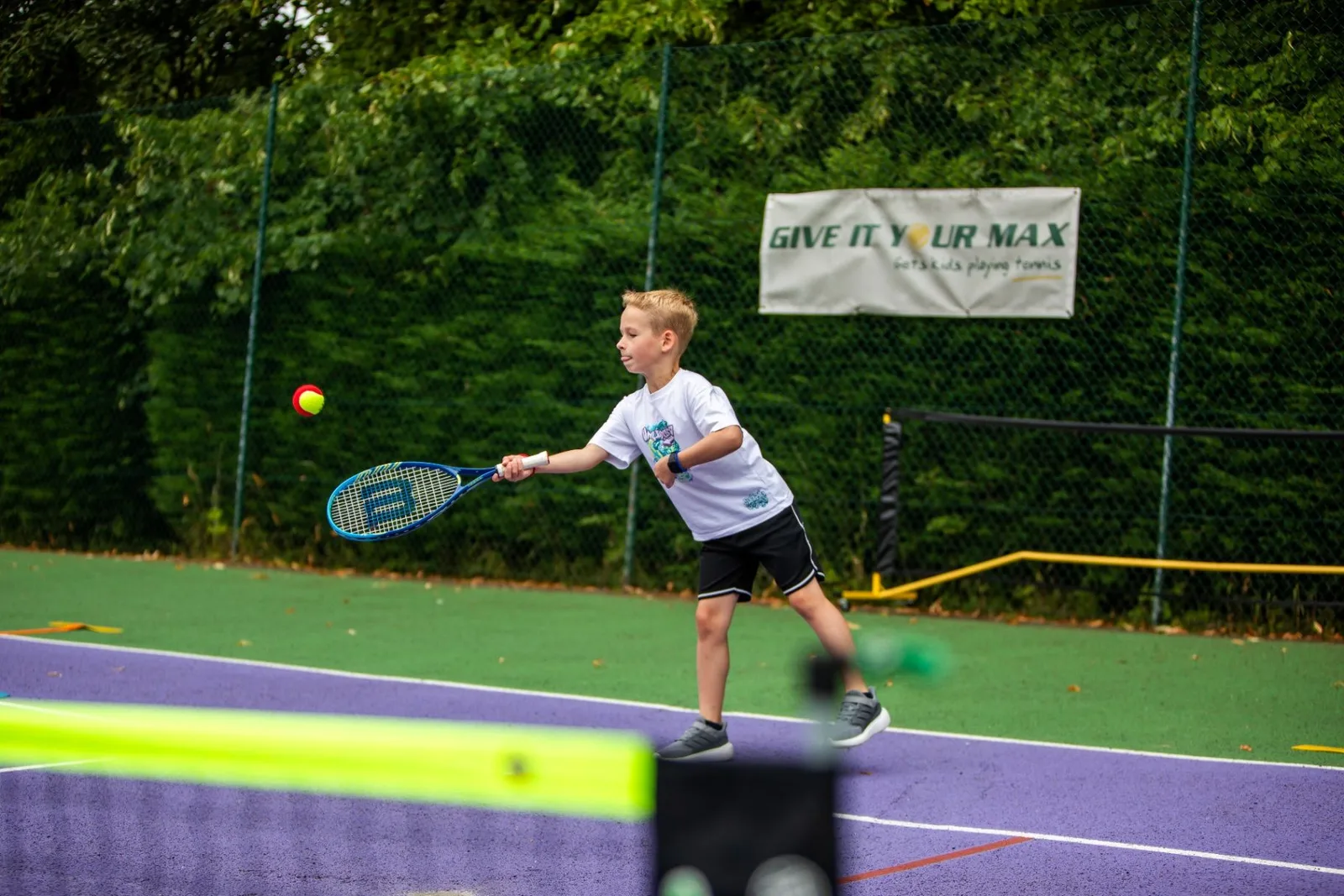 Young player striking a forehand on an outdoor court
