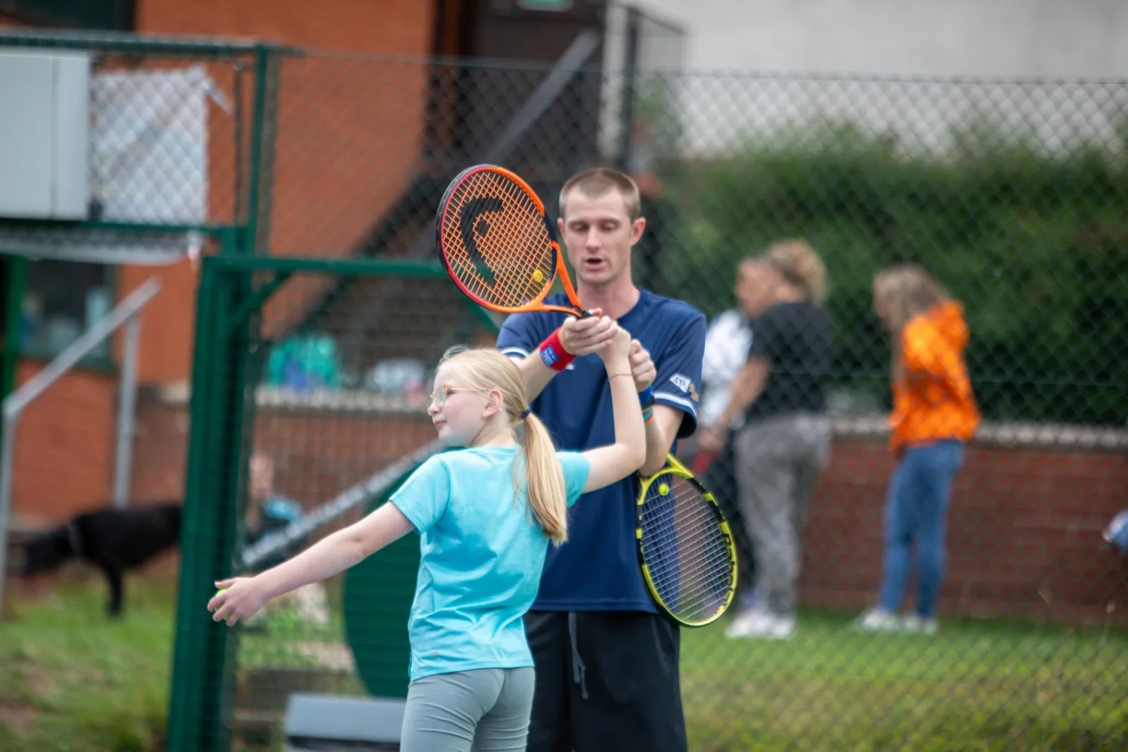 Coach helping a young player with racket technique