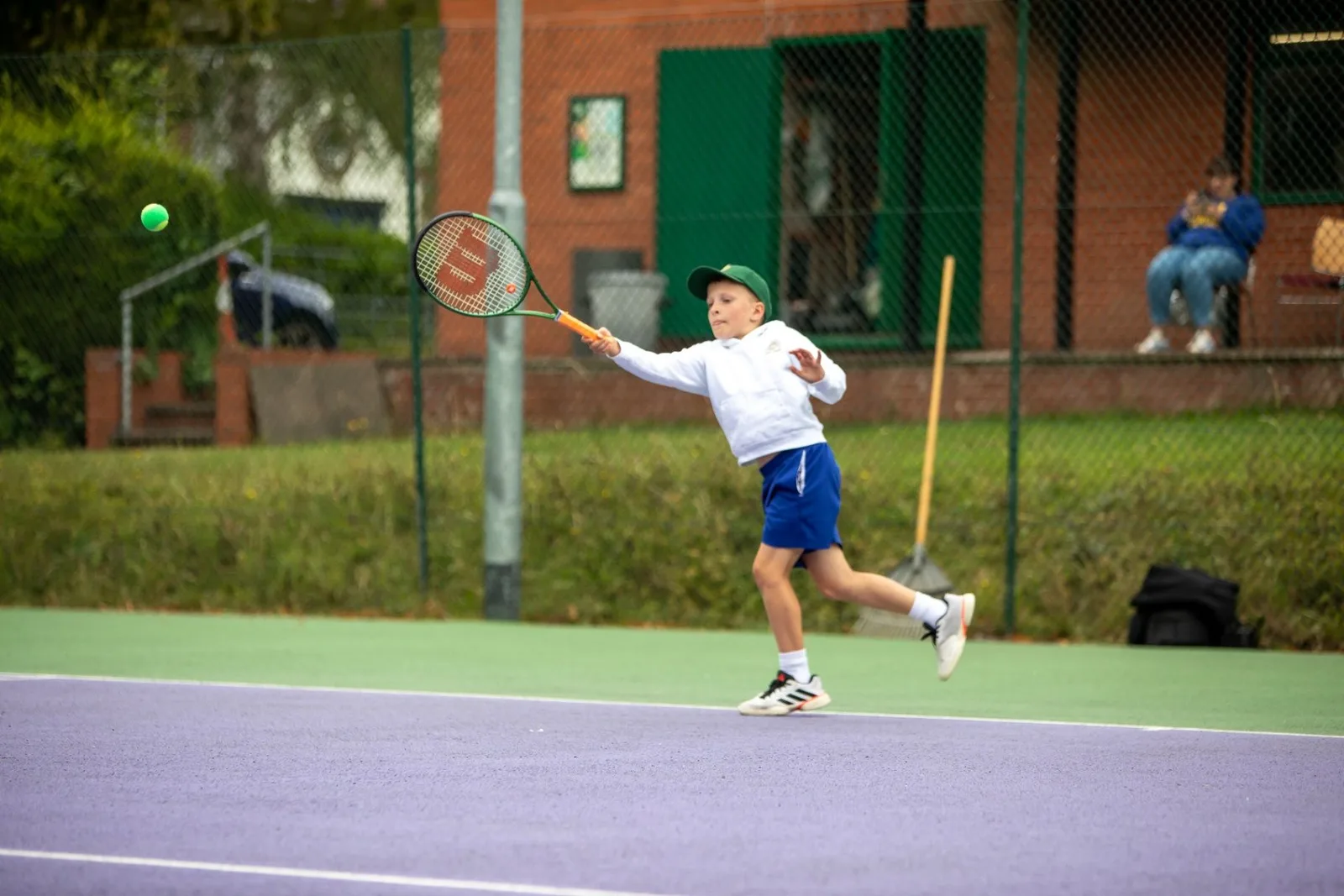 Young player striking a forehand on an outdoor court